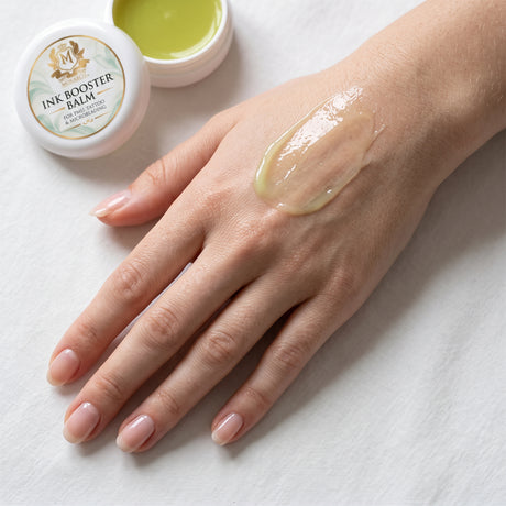 Skin Monarch Ink Booster Balm 30ml, bálsamo brillante extendido en el dorso de una mano